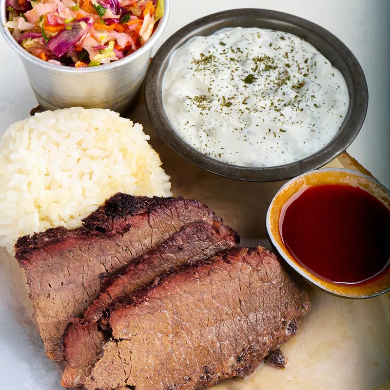 Brisket plate with tzatziki, rice, carrot and cabbage salad and bbq sauce.