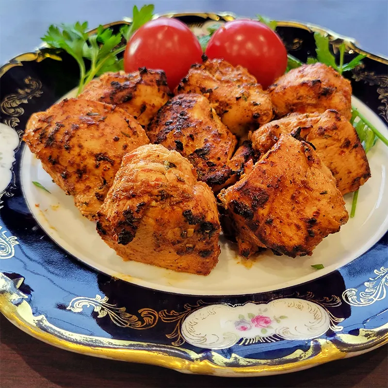 Plated grilled chicken with tomatoes and parsley.